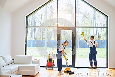 Cleaning concept. Young woman washing floor, while man cleaning window Stock Photo