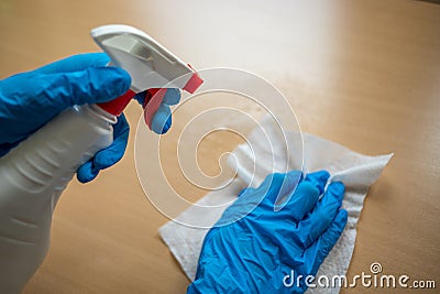 Cleaning home table sanitizing office table surface with disinfectant spray bottle washing surfaces with towel and gloves. COVID- Stock Photo