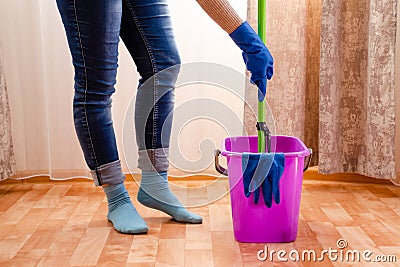 Cleaning the house with a lilac bucket, blue gloves, a mop and cleaning lady`s feet. Home cleaning concept Stock Photo