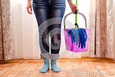 Cleaning the house with a lilac bucket, blue gloves, a mop and cleaning lady`s feet. Home cleaning concept Stock Photo