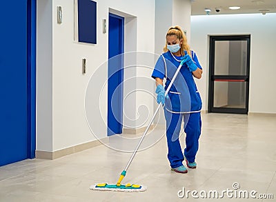 A cleaning lady with a mask on her face cleans the hallway Stock Photo