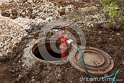 Cleaning manhole, sewer, repair, maintenance in sewerage hatchway using a pump and hose on construction site Stock Photo