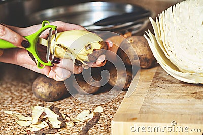 Cleaning potatoes. Woman`s hands clean potatoes special tool Stock Photo