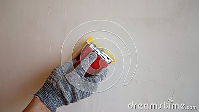 Peeling off uneven surfaces on a putty wall, sanding the freshly plastered wall surface with sandpaper. Cleaning putty Stock Photo