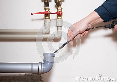 Cleaning the sewer drain pipe with a manual plumbing cable. Sewer blockage, close-up Stock Photo