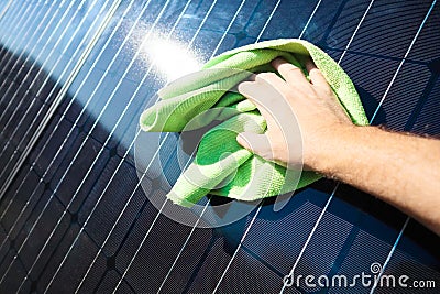 Cleaning solar panel with wipe. Hand wipes solar panels from dirt. Solar panel or photovoltaic module maintenance. Selective focus Stock Photo