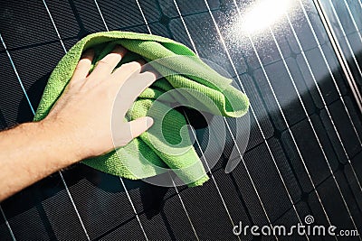 Cleaning solar panel with wipe. Hand wipes solar panels from dirt. Solar panel or photovoltaic module maintenance. Selective focus Stock Photo