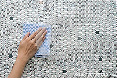 Cleaning tile wall by woman hand Stock Photo