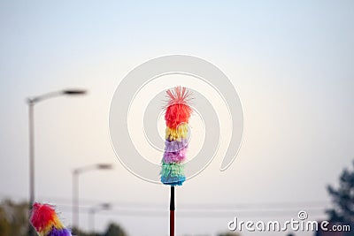 Selective blur on a rainbow feather duster, multicolor, made of artificial feathers, on display outdoors. Stock Photo