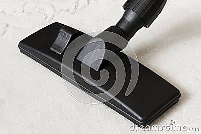 Cleaning white carpet with a vacuum cleaner and black universal nozzle. Stock Photo