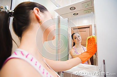 Cleanness in every move. Pretty brunette cleans mirror Stock Photo