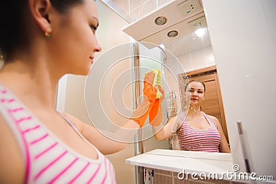 Cleanness in every move. Pretty brunette cleans mirror Stock Photo