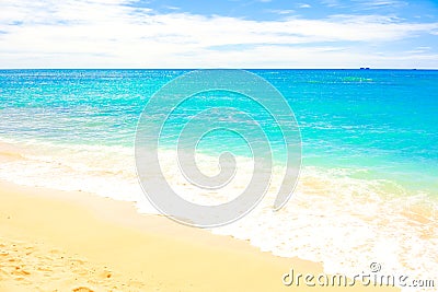 Clear blue ocean water coming onto sandy beach with seafoam Stock Photo