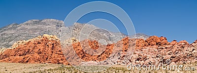 Clear blue sky above red the striped rock outcrops and hilss of Stock Photo