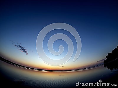 clear evening sky over a calm lake with a lone cloud Stock Photo