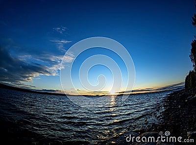 clear evening sky over a calm lake with a lone cloud Stock Photo