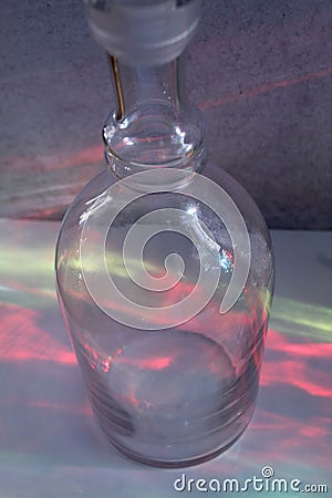 Clear glass bottle with rainbow like reflections of other colored bottles red, green, yellow, blue Stock Photo