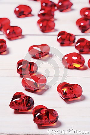 Clear glass effect plastic hearts on a white wooden table. Stock Photo