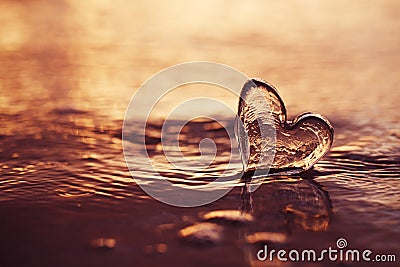 Clear glass heart on sand beach with sunrise sun light Stock Photo