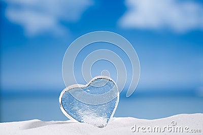 Clear glass heart on white sand beach glitter glass and reflec Stock Photo