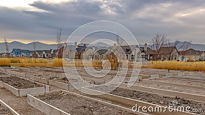 Clear Panorama Raised garden beds with homes and mountain against cloudy sky in the background Stock Photo