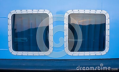 2 clear ship window with rectangle shape reflection and blue wall color Stock Photo