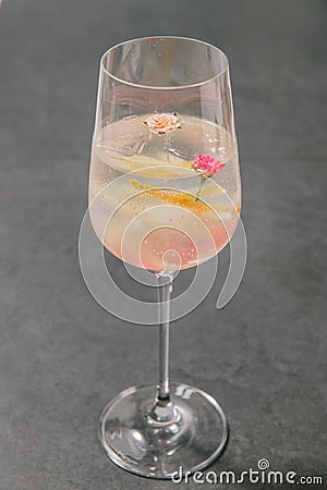 A clear sweet pink sparkling beverage decorated with fruit peels and small roses in a champagne glass. Stock Photo