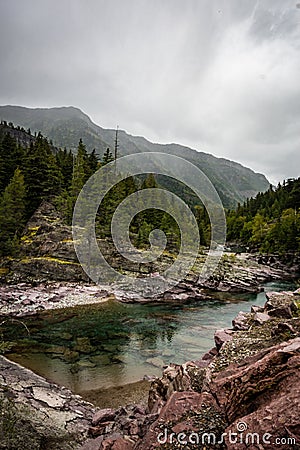 Clear teal waters of Haystack Creek along Going to the Sun Road in Glacier National Park. Overcast cloudy day Stock Photo