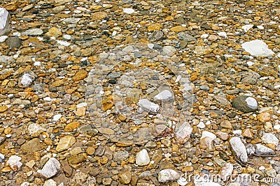 through clear water, small colored stones are visible Stock Photo