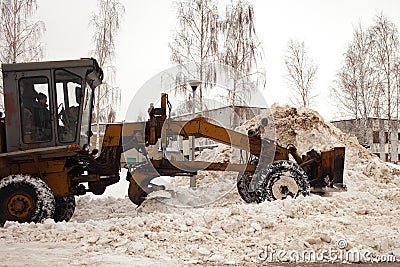 Clearing snow in Russia. Grader clears the way after a heavy snowfall. Tractor clears the road in the courtyard of a multi-storey Editorial Stock Photo