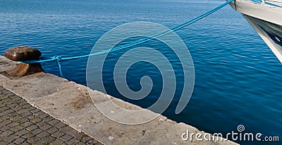 Cleat with blue hawser on the blue sea and white boat Stock Photo
