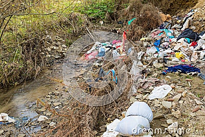 Cleen little creek contaminated with household waste, conceptual human negligence image. Editorial Stock Photo