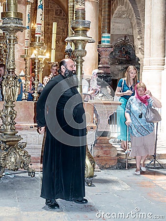 Clergyman stands in the hall in the Church of the Holy Sepulchre and greets visitors in the old city of Jerusalem, Israel. Editorial Stock Photo