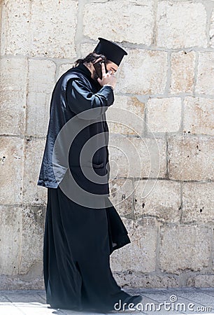 The clergyman stands and talks on his mobile phone in the old city of Jerusalem, Israel. Editorial Stock Photo