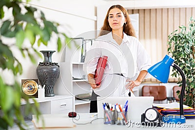 Clerical worker with folder in hands standing in office Stock Photo