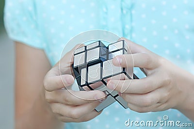 Clever child solves a mirror cube puzzle, a toy in the hands Editorial Stock Photo