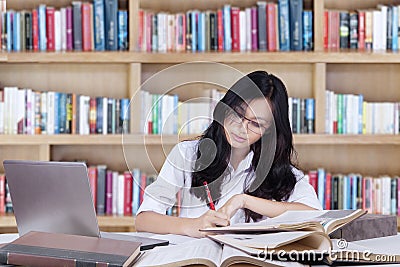 Clever teenage girl doing assignment in the library Stock Photo