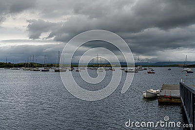 The Rosmoney Pier and dock with many sailboats and yachts anchored in the waters of Clew Bay under an overcast sky Editorial Stock Photo