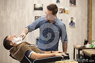 Client getting beard shaving in barber shop Stock Photo