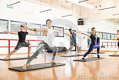 Clients Performing Warrior Pose Ii On In Health Club Stock Photo