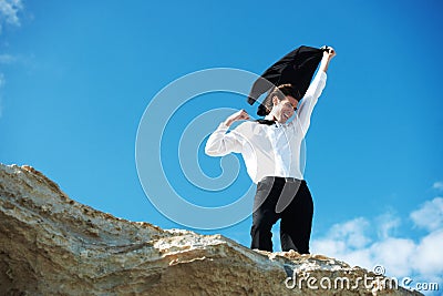 Cliff, business and man with celebration, excited and victory with holiday, smile and winning with promotion. Person Stock Photo