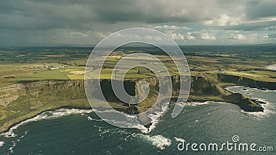 Cliff ocean Ireland coast aerial view: green grass meadows with little cottages in farmland Stock Photo