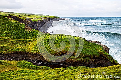 Cliffs of Moher at the Alantic Ocean in Western Ireland with waves battering against the rocks Stock Photo