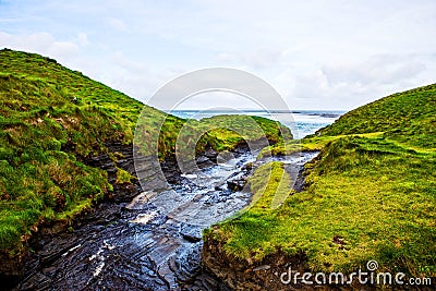 Cliffs of Moher with small creek at Alantic Ocean in Western Ireland with waves battering against the rocks Stock Photo