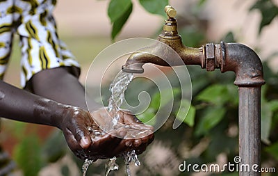 Climate Change Symbol: Handful Of Water Scarsity for Africa Symbol. Hand of an African black boy with water pouring from a tap. Stock Photo