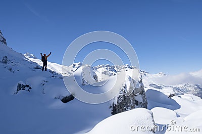 Climber or alpinist at the top of a mountain. A success of mountaineer reaching the summit. Outdoor adventure sports in winter Stock Photo
