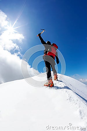 Climber reaches the summit of a snowy mountain peak Stock Photo