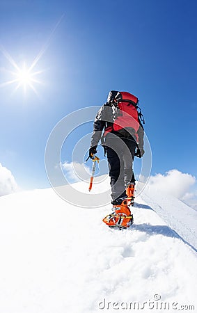 A climber reaching the summit of a snowy mountain peak. concept: overcome adversity, achieve goals Stock Photo