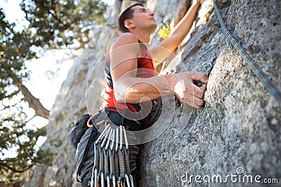 Climber in red t-shirt climbs a gray rock. A strong hand grabbed the lead, selective focus. Strength and endurance, climbing Stock Photo