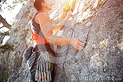 A climber in a red t-shirt climbs a gray rock. A strong hand grabbed the lead, selective focus. Strength and endurance, climbing e Stock Photo